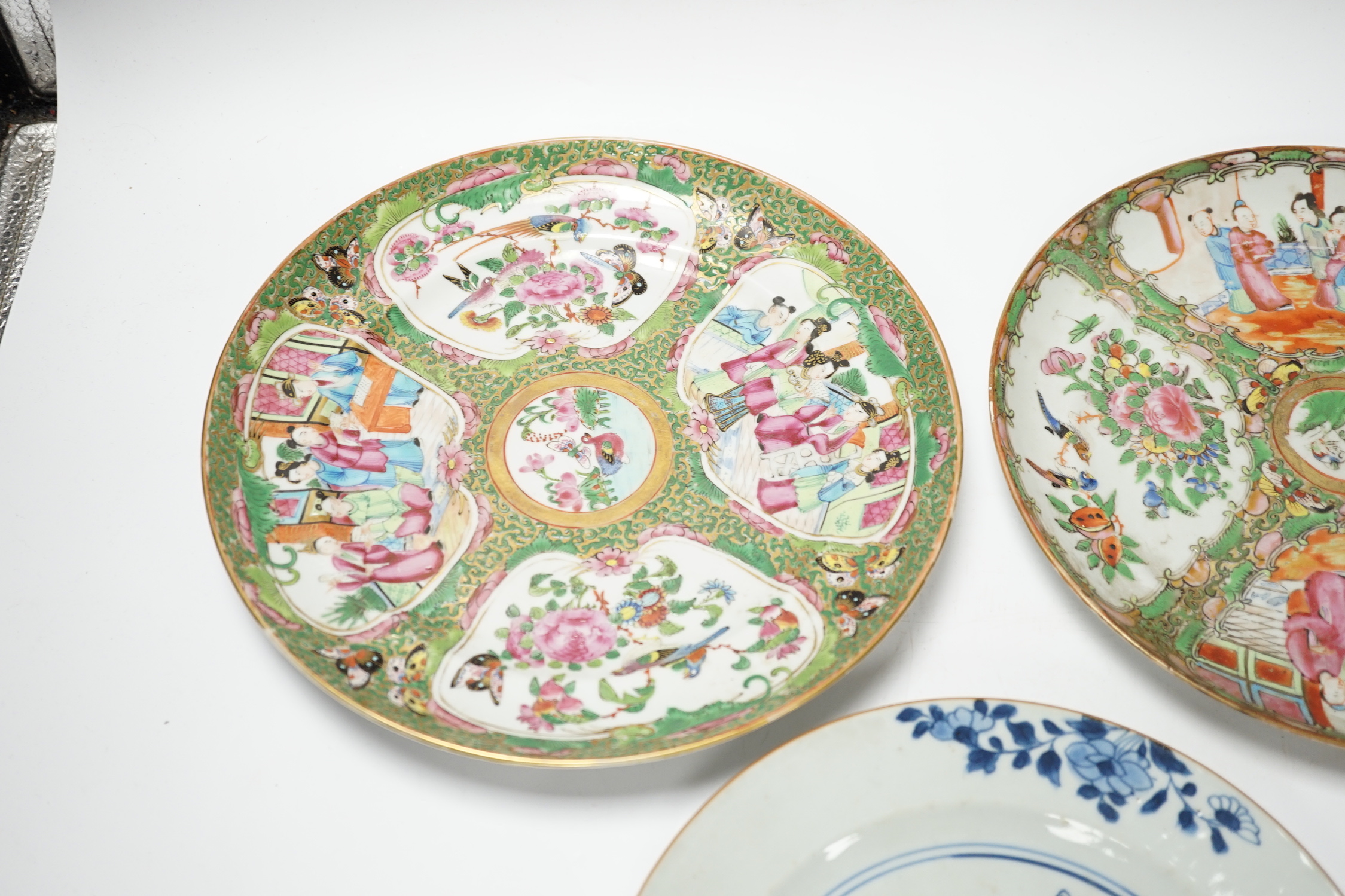 Two 19th century Chinese famille rose plates and an 18th century blue and white plate, 24cm in diameter